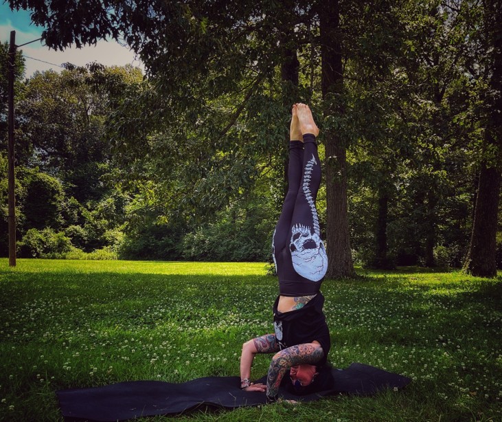 person with tattoos doing yoga headstand